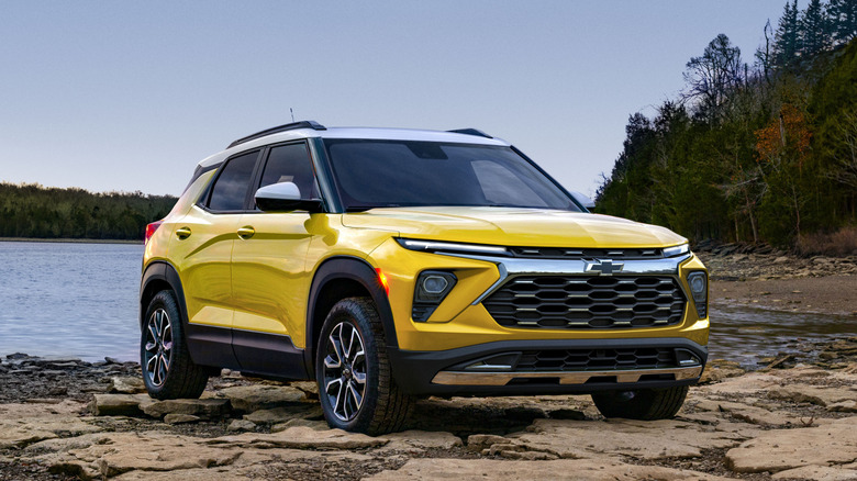 A Nitro Yellow 2026 Chevrolet Trailblazer parked near a body of water on some rocks.