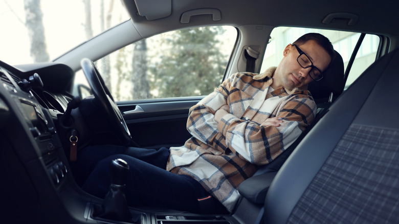 A tired driver sleeping inside the car