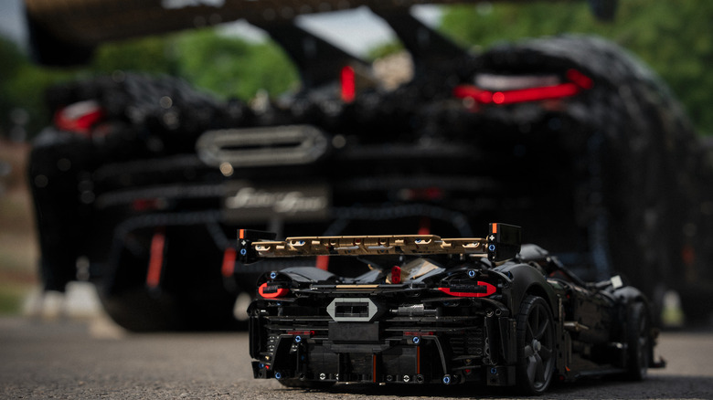 The rears of the 1:8 scale Koenigsegg Sadair's Spear Lego Technic model in focus in front of the rear of the full-scale working Koenigsegg Sadair's Spear