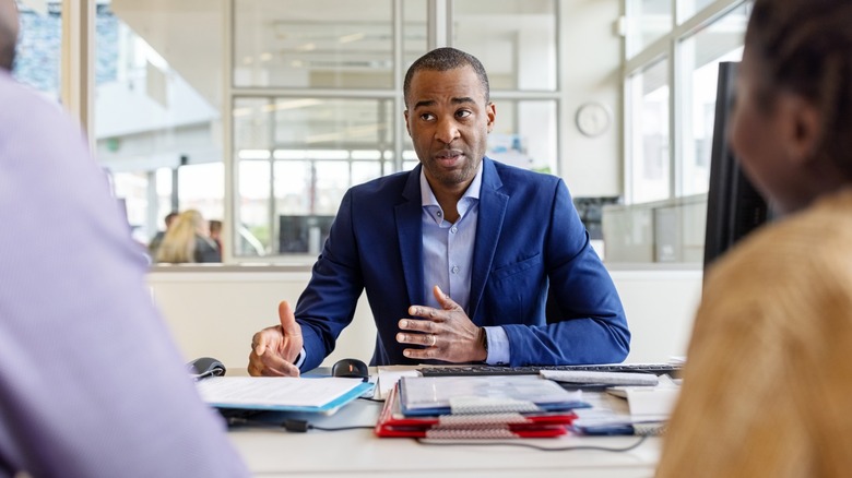 Car salesman meeting with a couple in his office