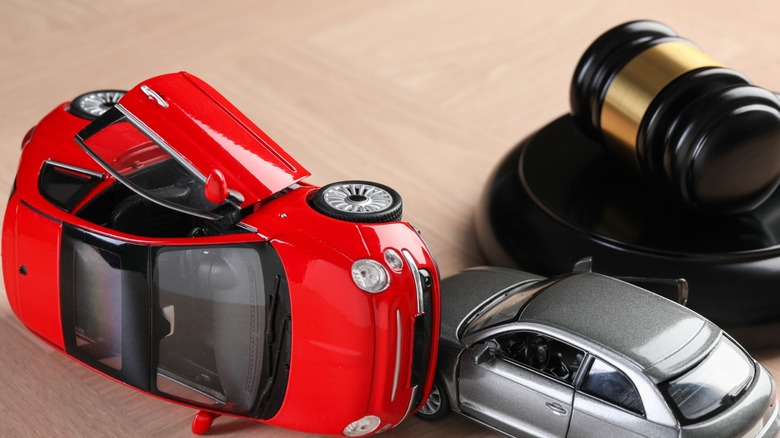 Judge's gavel next to two toy cars.