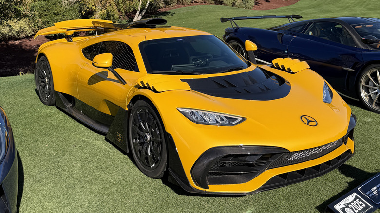Front 3/4 view of a yellow Mercedes-AMG One on a golf course
