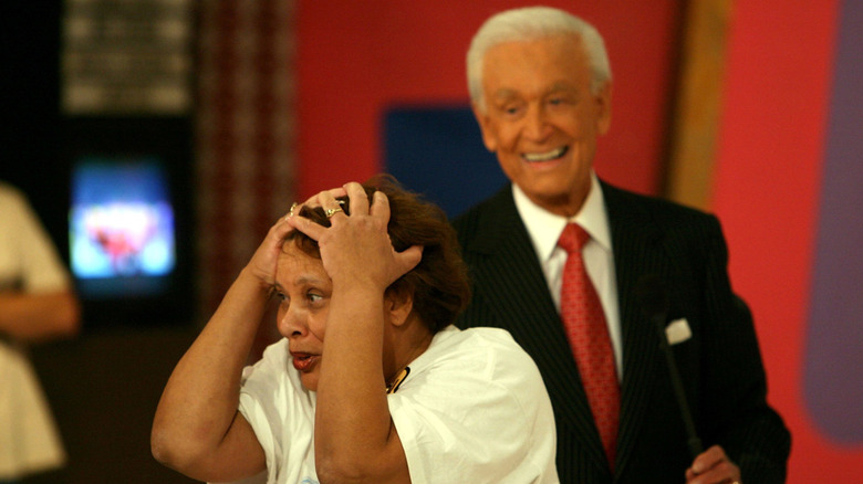 A contestant reacts after winning a new car on "The Price is Right" with former host Bob Barker in the background.