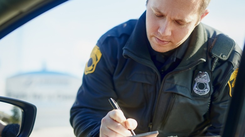A police officer writing a ticket during a traffic stop.