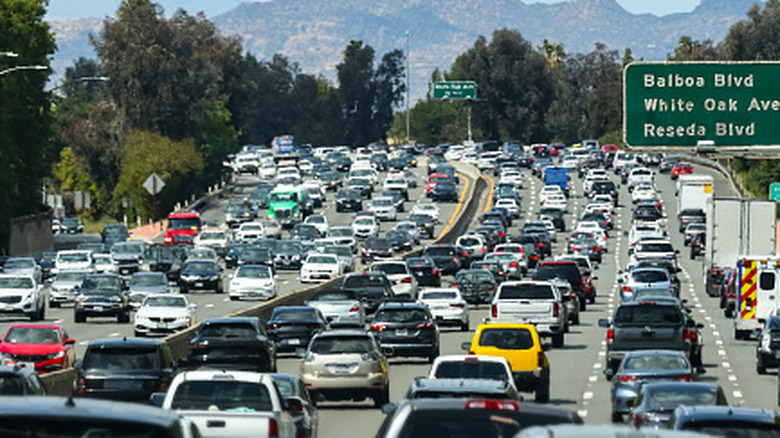 A traffic jam in Los Angeles, with five clogged lanes on each side of a divider, and street signs for Balboa Boulevard, White Oak Avenue, and Reseda Boulevard