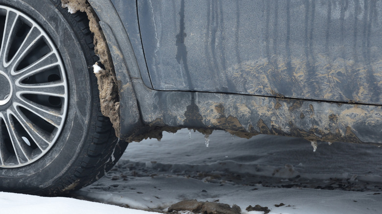 A rusty car frame in the snow.