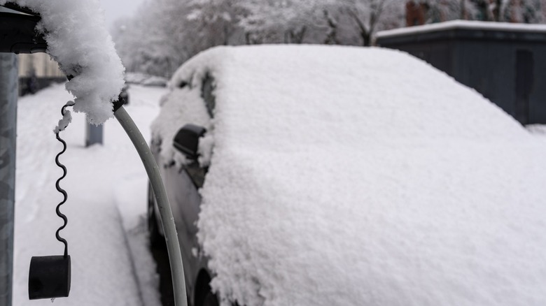 A snow-covered EV next to a charging station