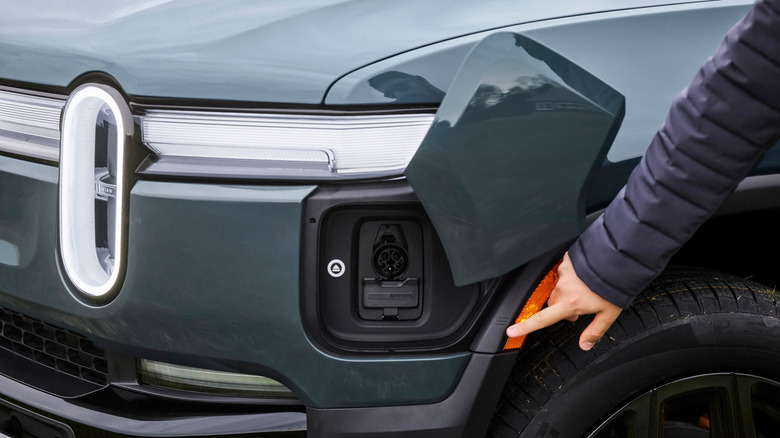 Man pointing to charge port on a Rivian EV