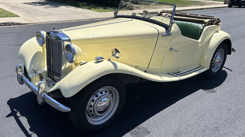1952 MG TD Roadster in buttercream yellow sitting in the sun in the middle of a road
