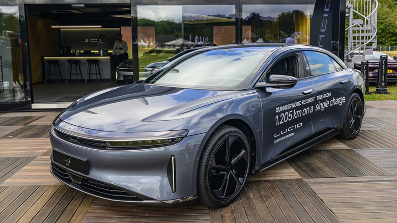 A blue Lucid Air sedan with a sign on the side noting it meets the Guinness World Record of the farthest drive on a single charge at 1,205 km