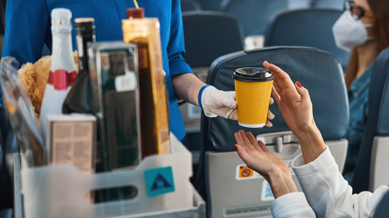 A passenger appropriately interacts with the flight attendant during beverage service.
