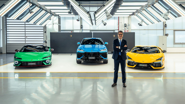 Umberto Tossini, former CPCOO for Lamborghini, poses with three Lamborghini models in the background.