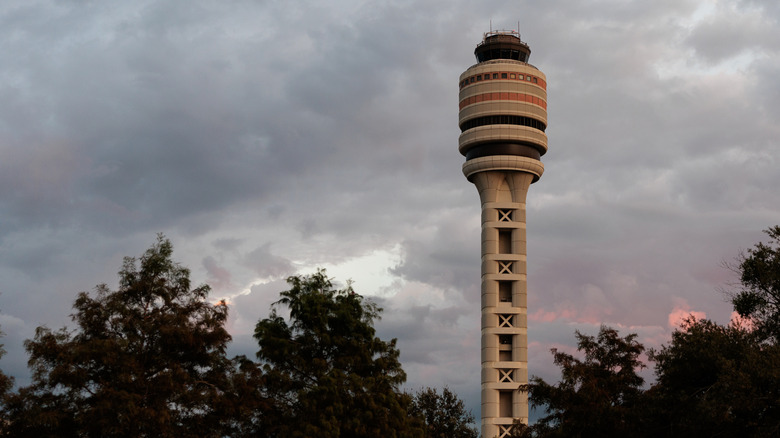The air traffic control tower at Orlando International Airport against a cloudy dusk sky