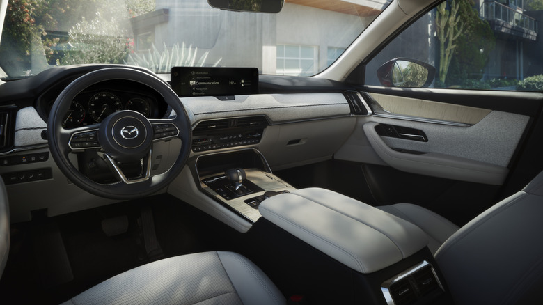 The white dashboard in a CX-90 with plants and a building visible out the windows