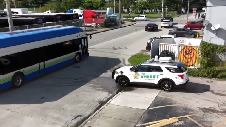 The autonomous police vehicle pulling out of a parking lot, waiting for a bus to pass.