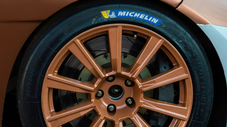 A closer view of a sports car wheel with a bronze rim wrapped in a Michelin racing tire