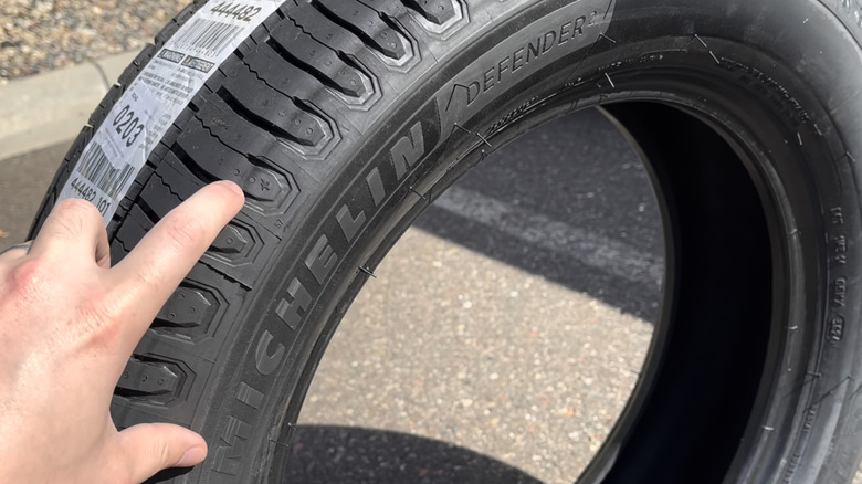 A finger points to the tread on a Michelin Defender2 all-season tire