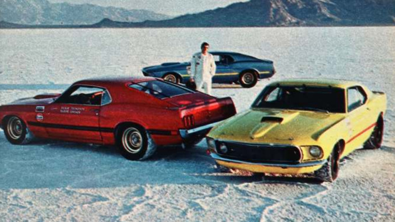 Three Ford Mustang Mach 1 race cars, one blue, one red, and one yellow, at Bonneville in 1968