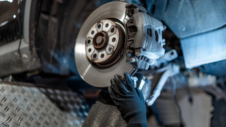 Gloved hand working on car brakes in a workshop