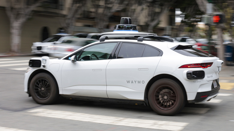 Side view of a Waymo Jaguar I-Pace driving through a city intersection