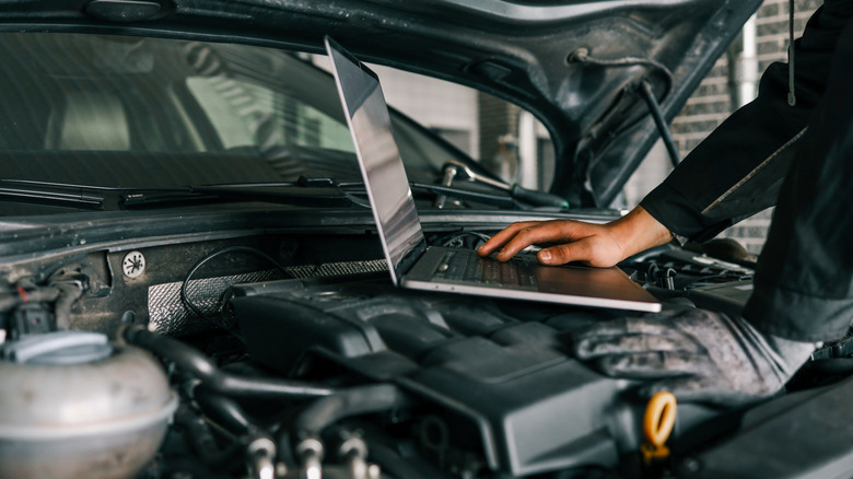 A using a laptop on top of a car's engine
