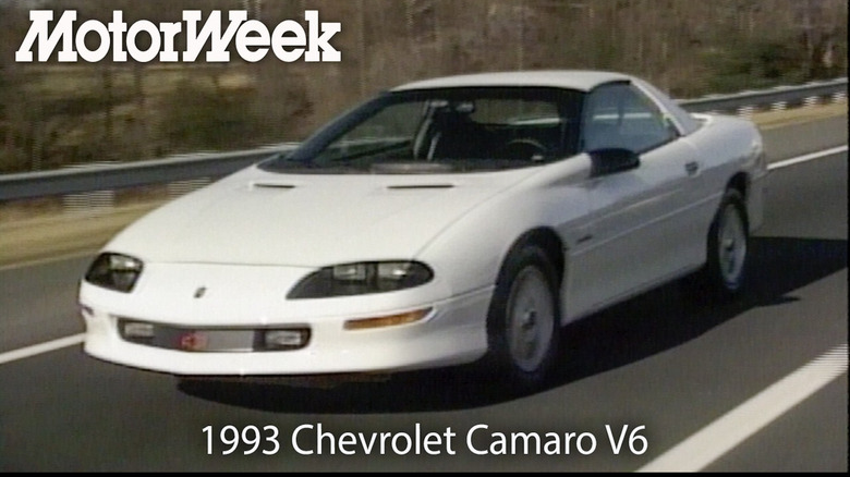 Front three-quarters shot of the white '93 Camaro driving on a road with the MotorWeek logo and model info in white text