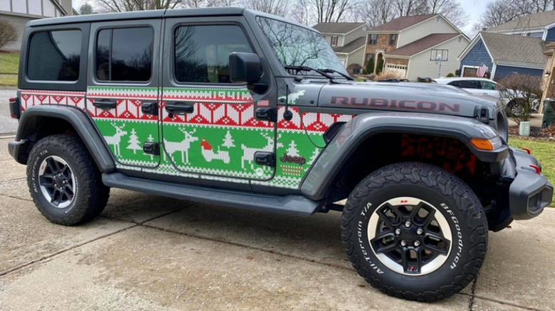 A side photo of a gray Wrangler Unlimited with the green and red holiday Trail Armor parked in front of homes