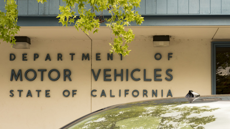 California DMV sign outside one of its buildings with a car in the foreground