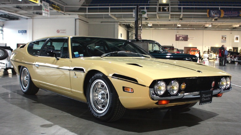 A gold Lamborghini Espada parked at an indoor auto show