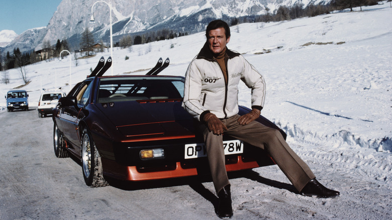 Roger Moore as James Bond posing with a red Lotus Esprit