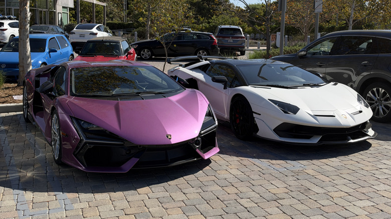 A pink Lamborghini Revuelto next to a white Lamborghini Aventador SVJ