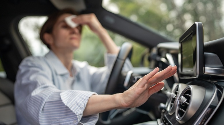 Driver wipes sweat while trying to feel cold air from the air conditioning vents