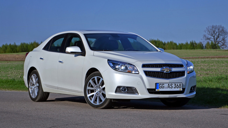 A white Chevy Malibu parked near grass.