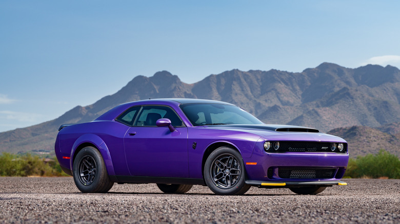A dark purple Dodge Demon SRT 170 parked outside in front of a mountain range.
