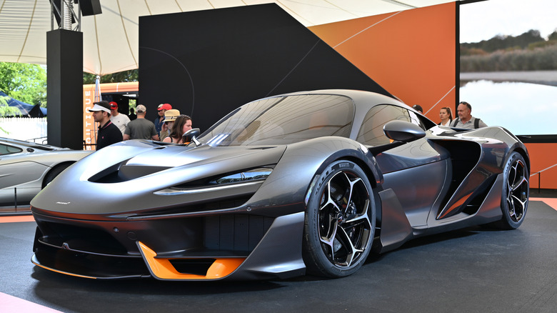 A matte black McLaren W1 with orange accents on display inside the McLaren tent at the Goodwood Festival of Speed.