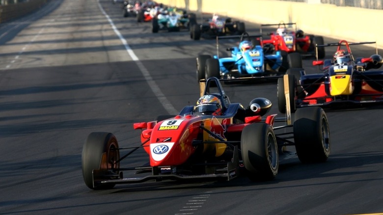 Formula 3 race cars approach a curve in front of the camera at the 2008 Macau Grand Prix
