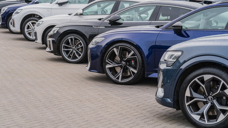A row of Audi sedans is parked in a lot.