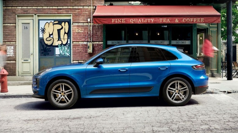 A blue Porsche Macan parked on a city street in front a tea and coffee shop