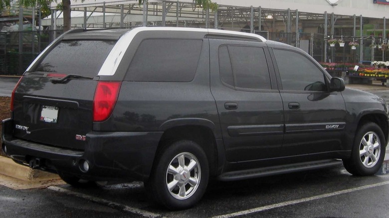 A black GMC Envoy XUV parked in front of a garden supply store