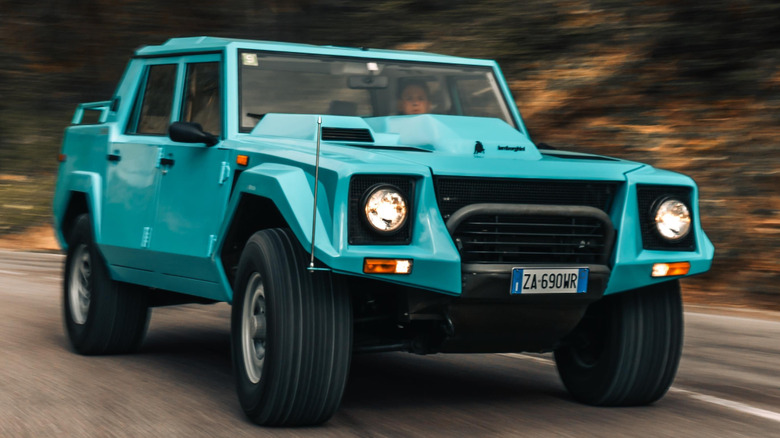 A turquoise Lamborghini LM002 SUV rounding a bend in the road