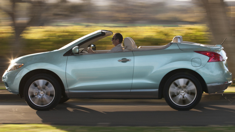 A pale green Nissan Murano CrossCabriolet with its top down hustling down a road