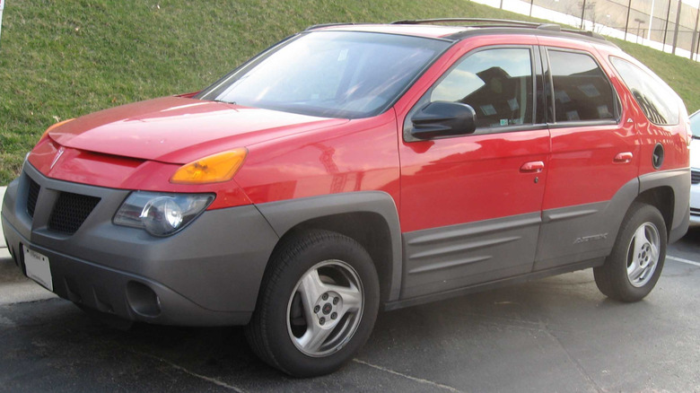 A red 2001 Pontac Aztek parked in front of a grassy hill