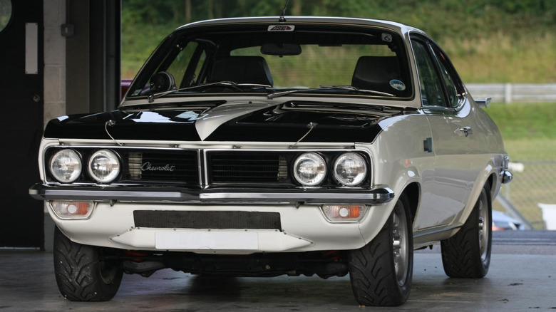 A white Chevrolet Firenza Can-Am with a black hood parked inside.
