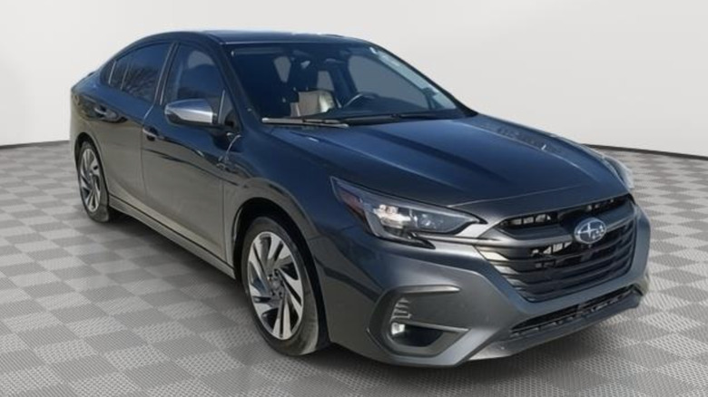 a gray subaru legacy parked in a white room on a gray checkerboard floor