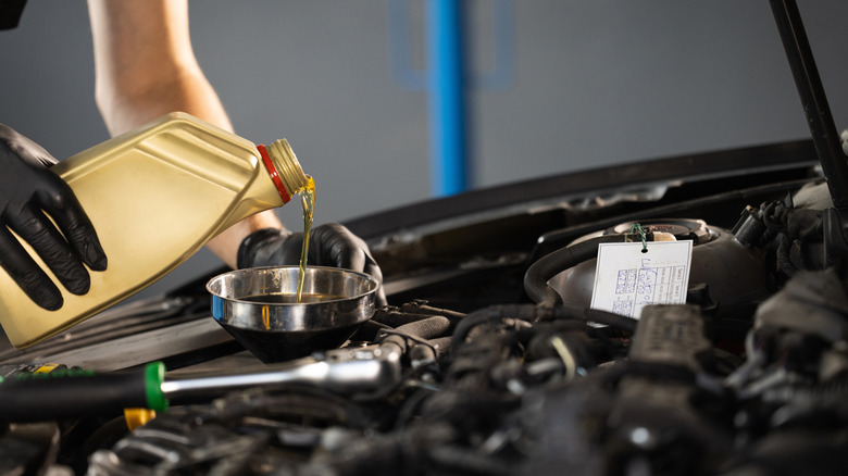 A close up of pouring fresh new motor oil into a car's engine.