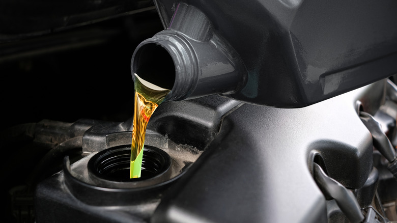 A container of oil being poured into a car