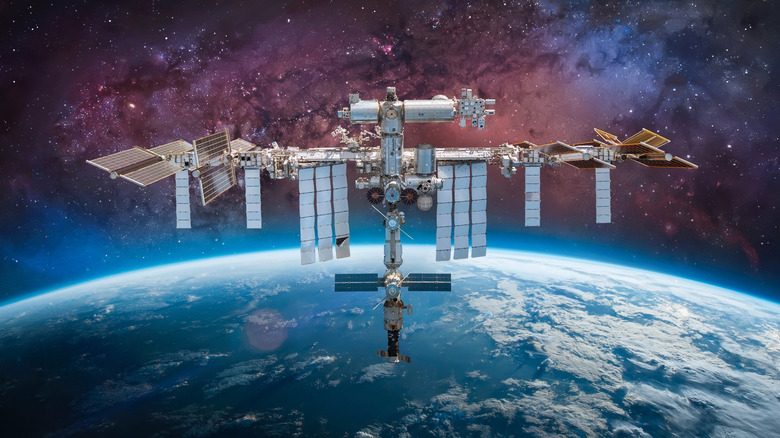 The International Space Station floats above the Earth against a starry sky
