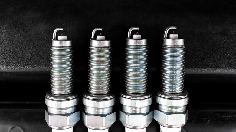Four new iridium spark plugs against a dark background