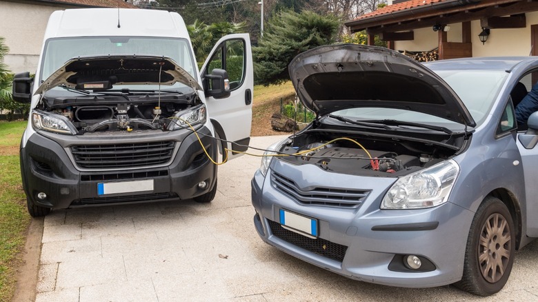 A white van jump starting a gray car
