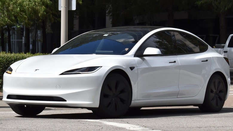 A white Tesla Model 3 in a parking lot